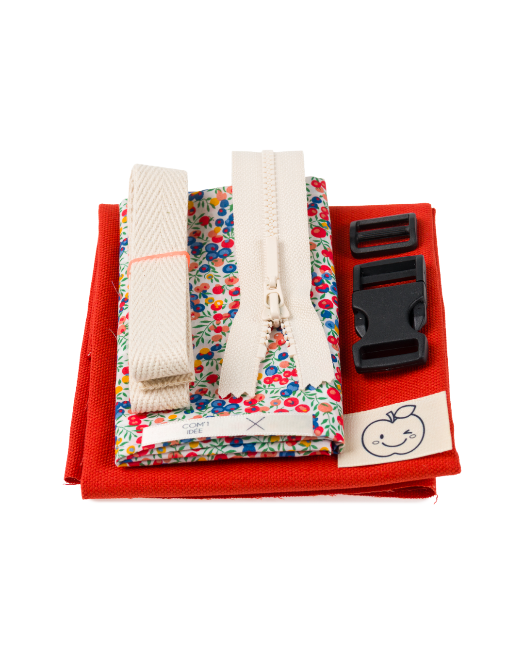 Contenu du kit couture enfant Élie comprenant tissu rouge, doublure Liberty à fleurs multicolores, sangle, fermeture éclair et accessoires de mercerie.