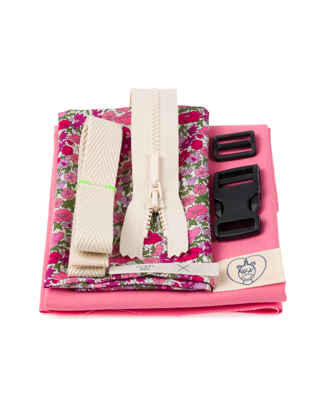 Contenu du kit couture enfant Mélo comprenant tissu rose, doublure Liberty, sangle, fermeture éclair et accessoires de mercerie.