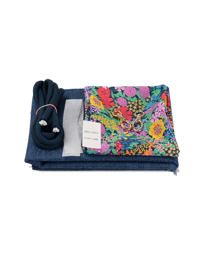Contenu du kit couture sac bourse Alix avec tissu denim bleu, tissu fleuri Liberty coloré, cordon bleu marine, mousquetons dorés et accessoires de couture.