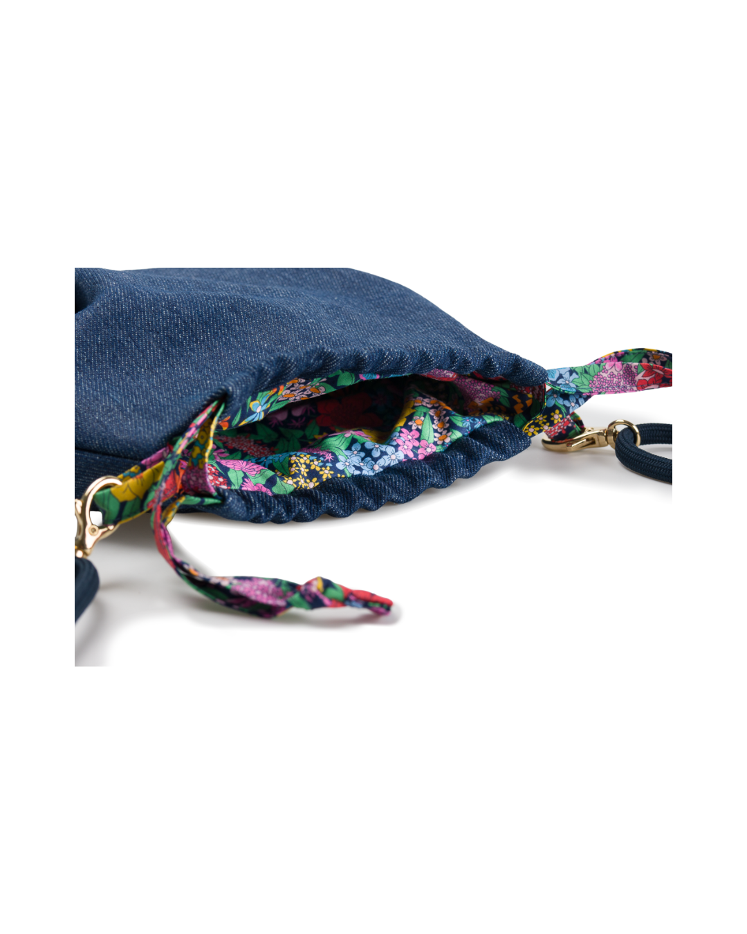 Gros plan sur l’ouverture du sac bourse Alix, révélant la doublure Liberty florale colorée et le système de fermeture coulissant.