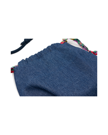Gros plan sur le tissu denim bleu du sac bourse Alix avec finition froncée et détails en tissu Liberty fleuri multicolore.