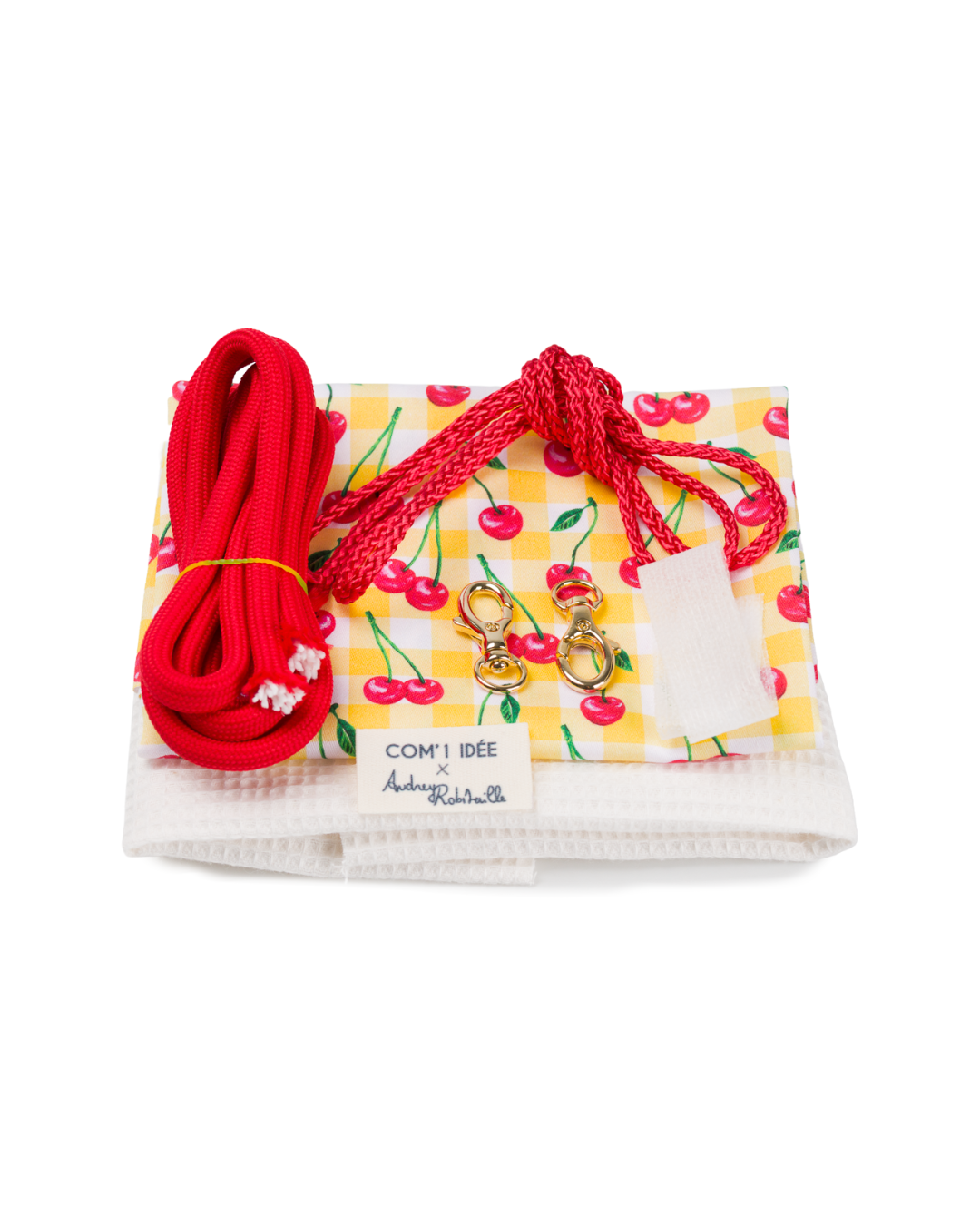 Contenu du kit couture sac bourse Telma avec tissu imprimé cerises, cordons rouges, mousquetons dorés et fournitures de couture.