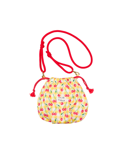 Sac bourse Telma terminé en tissu imprimé cerises sur fond vichy jaune, avec cordons rouges et bandoulière réglable.